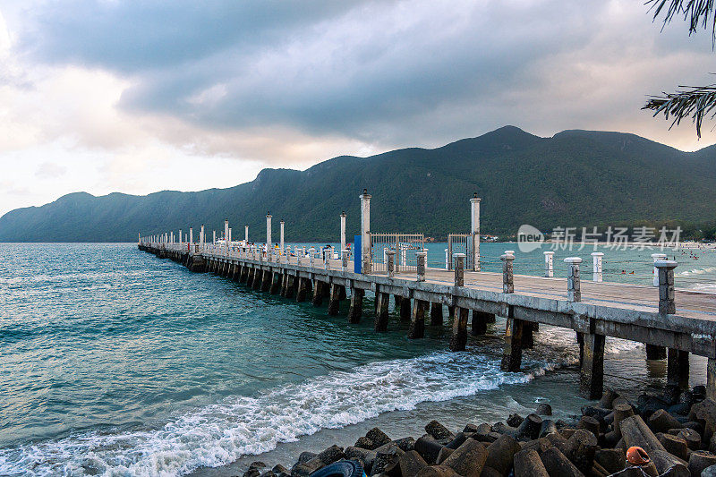 在越南宁静的Con Dao岛上的Con Son镇，新Con Dao客运港口的景色。海岸景观有波浪，海岸线，晴空，碧海，游客和山。